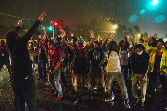 Protesters gesture as they stand in a street in defiance of a midnight curfew in Ferguson