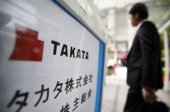 A man walks past a sign board of Japanese auto parts maker Takata Corp's Annual General Meeting in Tokyo