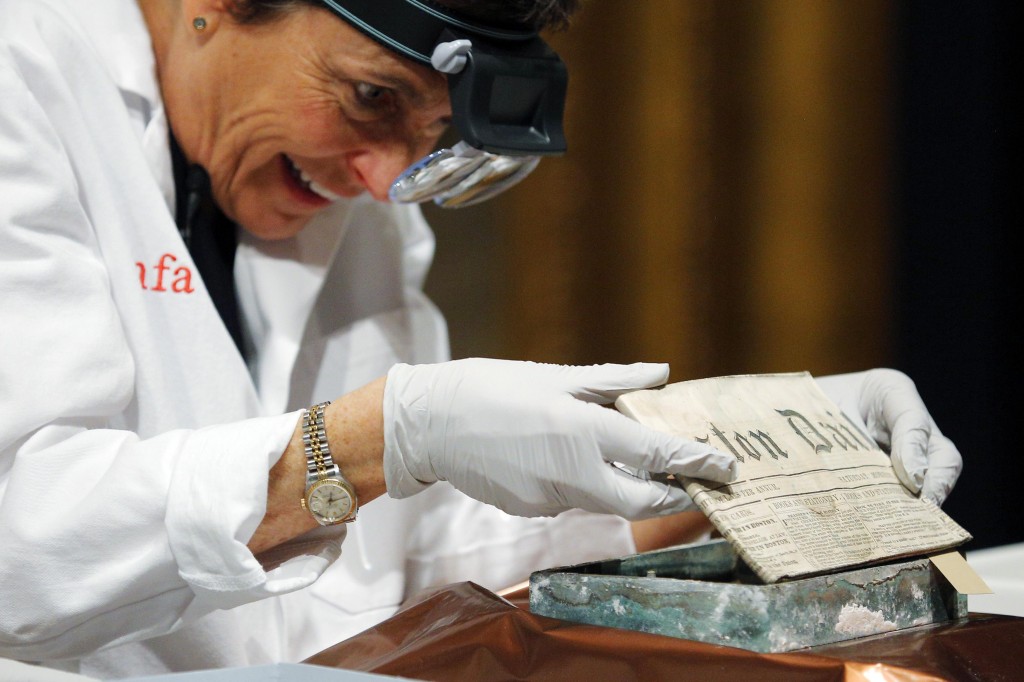 Conservator Pam Hatchfield removes a newspaper from a time capsule, which was placed under a cornerstone of the State House in 1795, at the Museum of Fine Arts, Boston