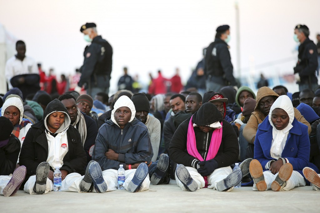 "Migrants rest after they disembarked in the Sicilian harbour of Augusta, April 16, 2015" 