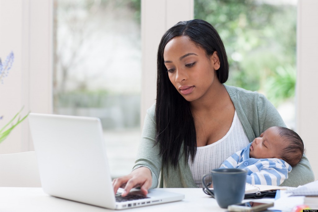 alt="Mother holding baby son and using laptop"
