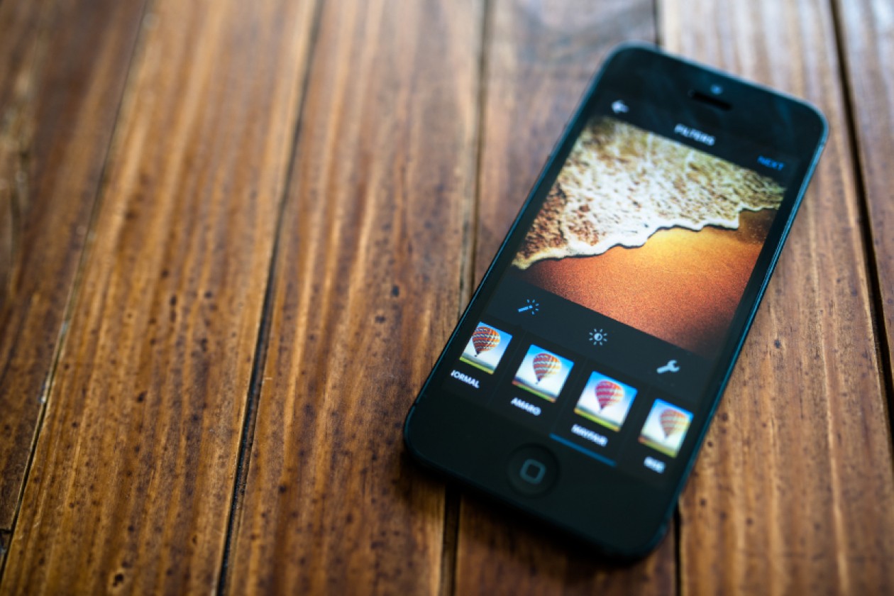 alt="iPhone on Wooden Surface Sports Instagram App"