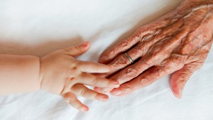 alt="Baby Hand Touches Old Woman's Hand"