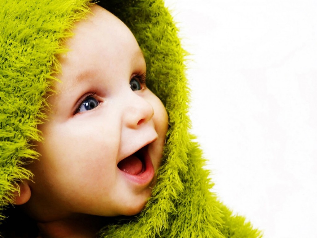 "smiling baby with green blanket"