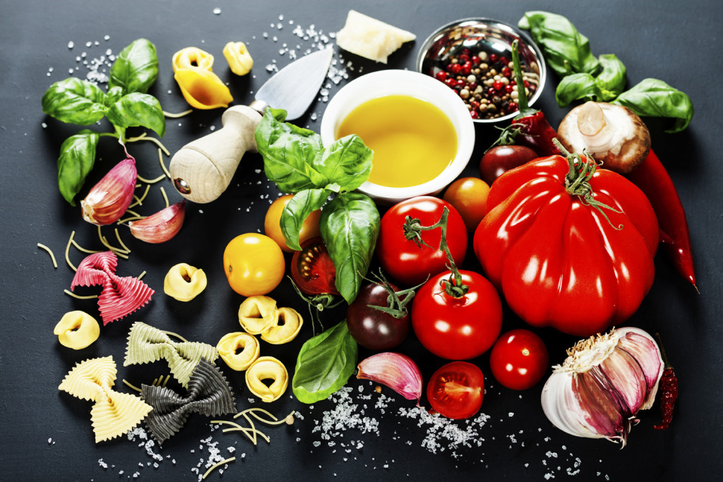alt="Italian ingredients - pasta, vegetables, spices, cheese - on dark background"