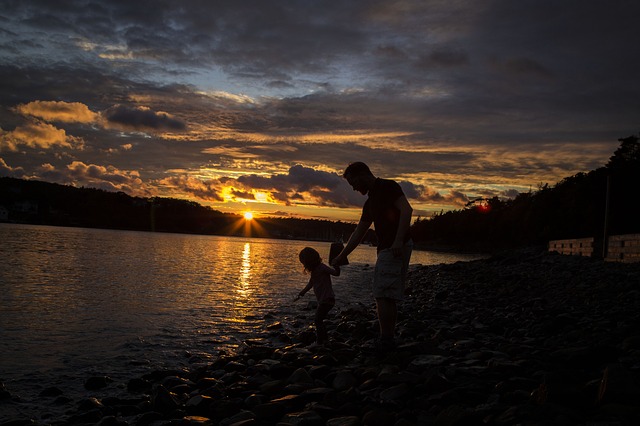 "Father and child by a lake at dusk."