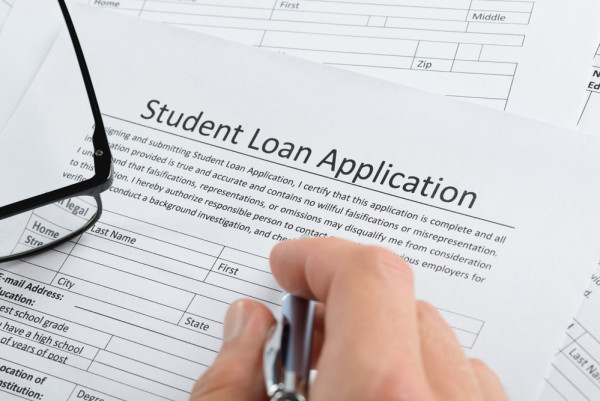 closeup of a hand with pen over a student loan application