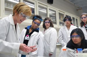 Female chief scientist showing an experiment to her students